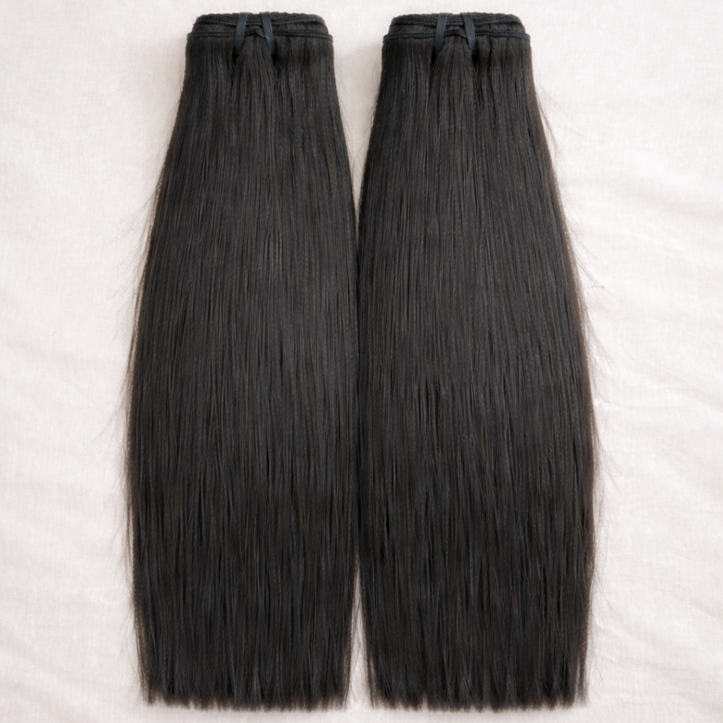 Two bundles of black hair extensions on a white background