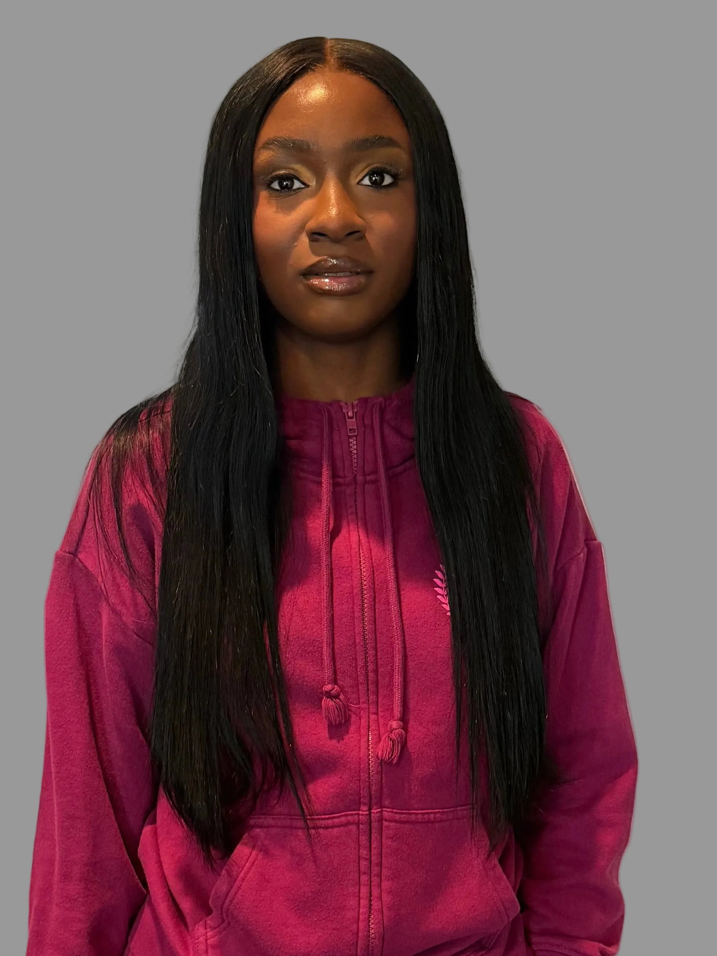 Person wearing a pink tracksuit standing in a room with white walls and wooden flooring.