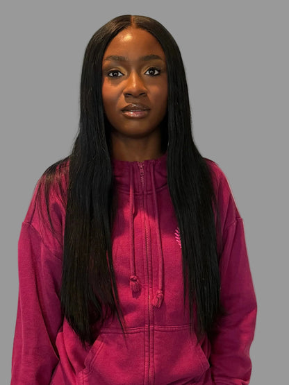 Person wearing a pink tracksuit standing in a room with white walls and wooden flooring.