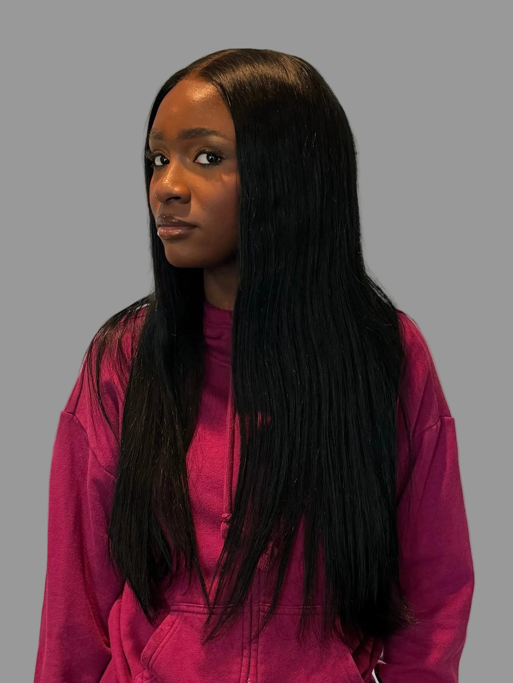 Person wearing a magenta outfit standing in a room with a mirror reflecting the interior.
