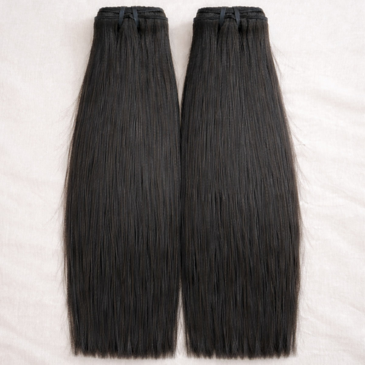 Two bundles of black hair extensions on a white background